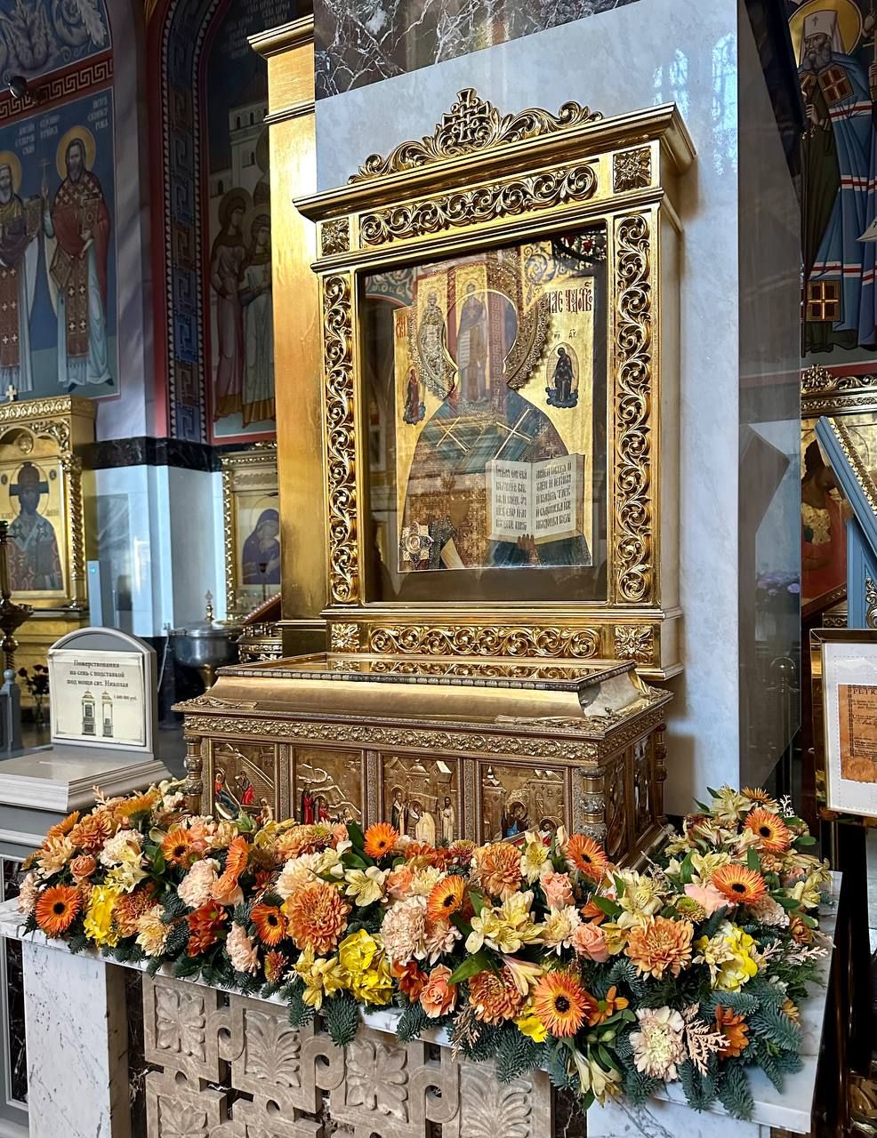 Оранжево-жёлтая композиция из гербер и хризантем у иконы в золочёном киоте